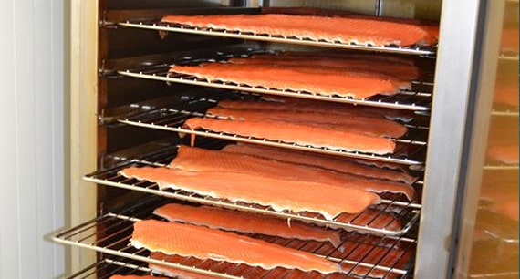 Filets de truite en cours de fumage dans un fumoir pour transformation de poisson